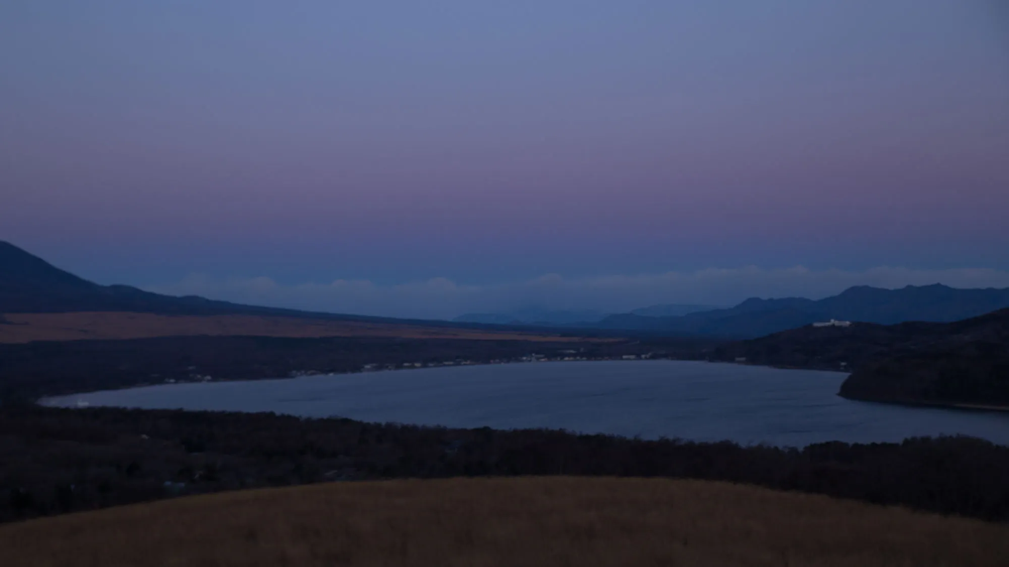 薄明かりの湖と山々の風景。